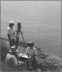 Black and white photo of Plate 5A. Survey team at the cemetery: Katherine May (standing), William B. Hafford (left), and Lada Onyshkevych (right).